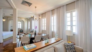 A hotel room with a wooden dining table, a sofa, and a chandelier. - Fera Palace Hotel (Salvador)