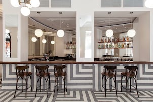 A bar area with a patterned floor, wooden bar counter, and hanging spherical light fixtures.