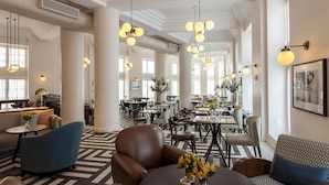 A spacious hotel lobby with high ceilings, modern lighting fixtures, and a mix of seating areas including sofas and chairs. - Fera Palace Hotel (Salvador)