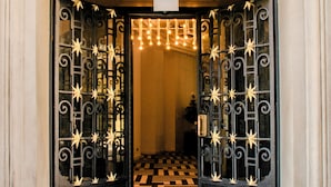 A grand entrance with a black wrought iron gate, a checkered floor, and an ornate white archway. - Fera Palace Hotel (Salvador)