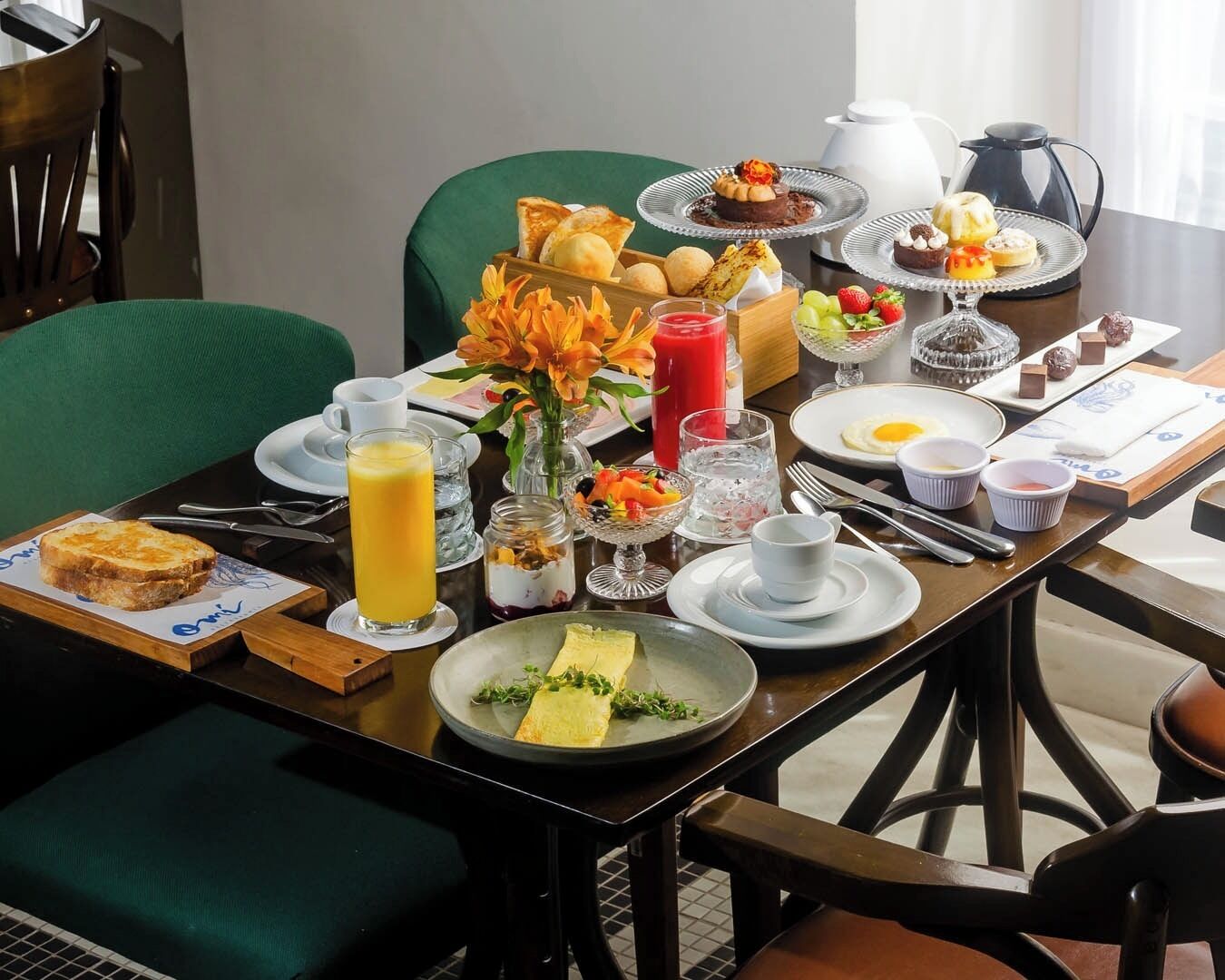 Mesa de café da manhã posta com diversos pratos, incluindo torradas, frutas e uma bebida quente.