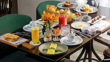 Mesa de café da manhã posta com diversos pratos, incluindo torradas, frutas e uma bebida quente.