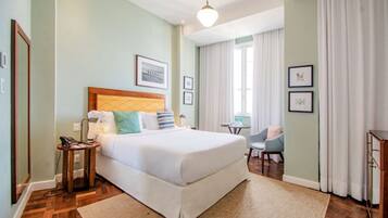Una habitación de hotel con una cama grande, una mesita de noche con teléfono, una silla y un escritorio con lámpara.