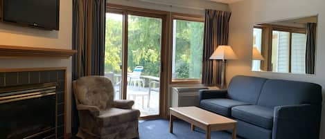 Una sala de estar con chimenea, un sofá, un sillón, una mesa y un televisor.