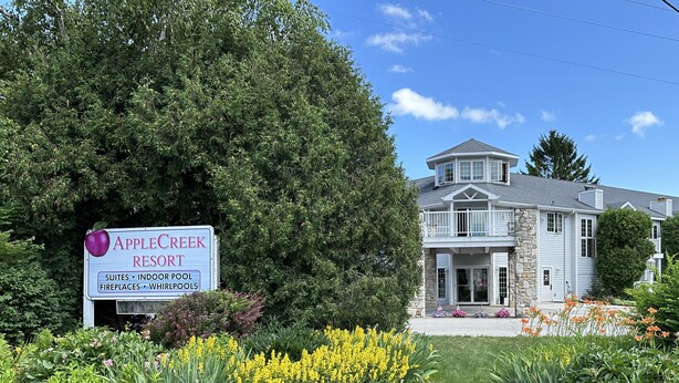 A sign for Apple Creek Resort with amenities like suites, indoor pool, fireplaces, and whirlpools.
