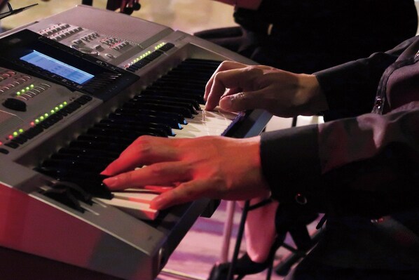 Une personne jouant d'un clavier doté d'un écran numérique et de divers réglages.