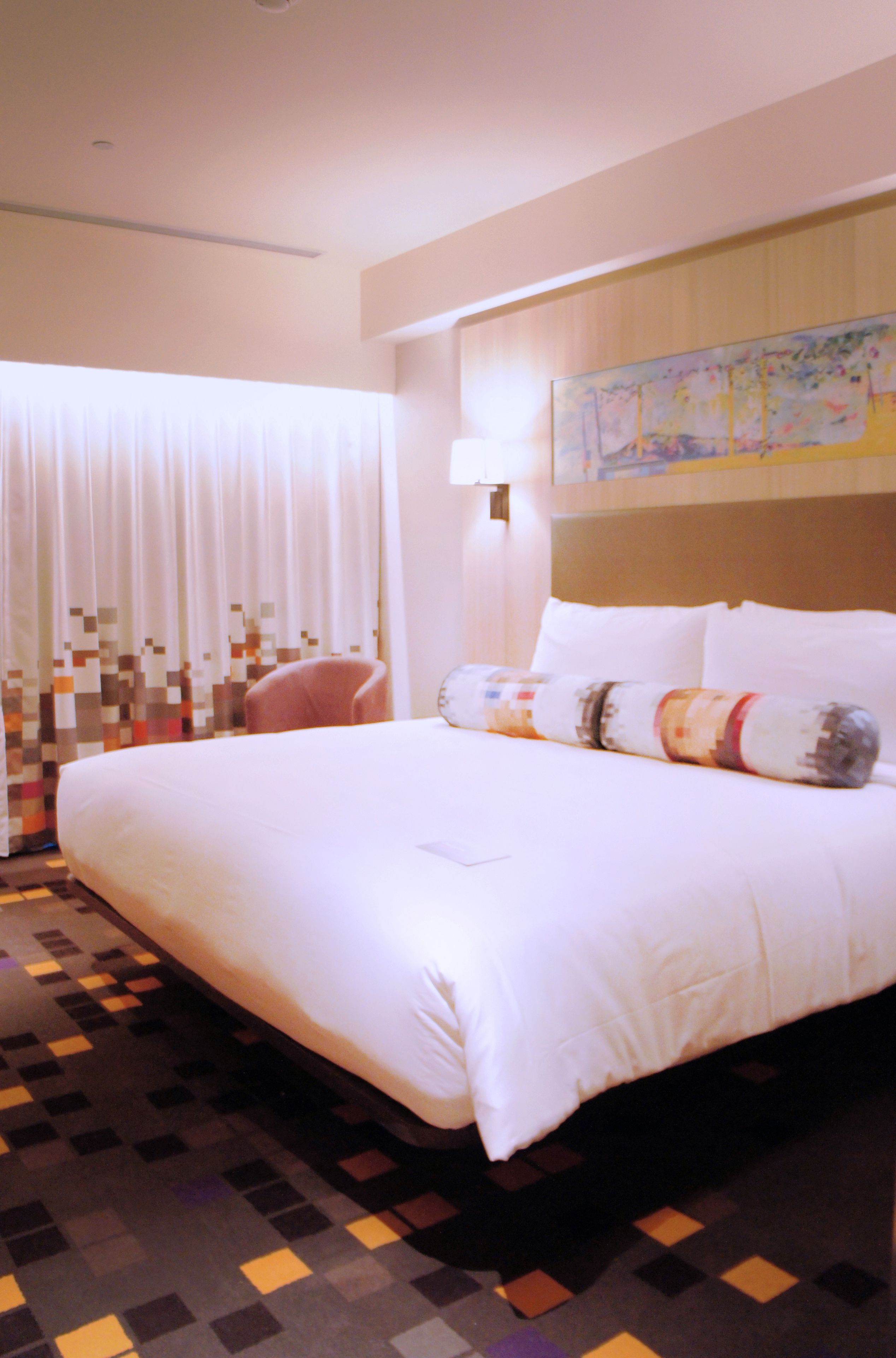 Een hotelkamer met een groot bed, een stoel, een wandlamp en een schilderij.