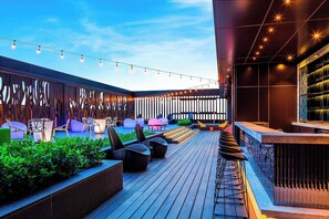 A rooftop bar with wooden flooring, outdoor seating, string lights, and a modern design. - Aloft Taipei Beitou (Taipei)