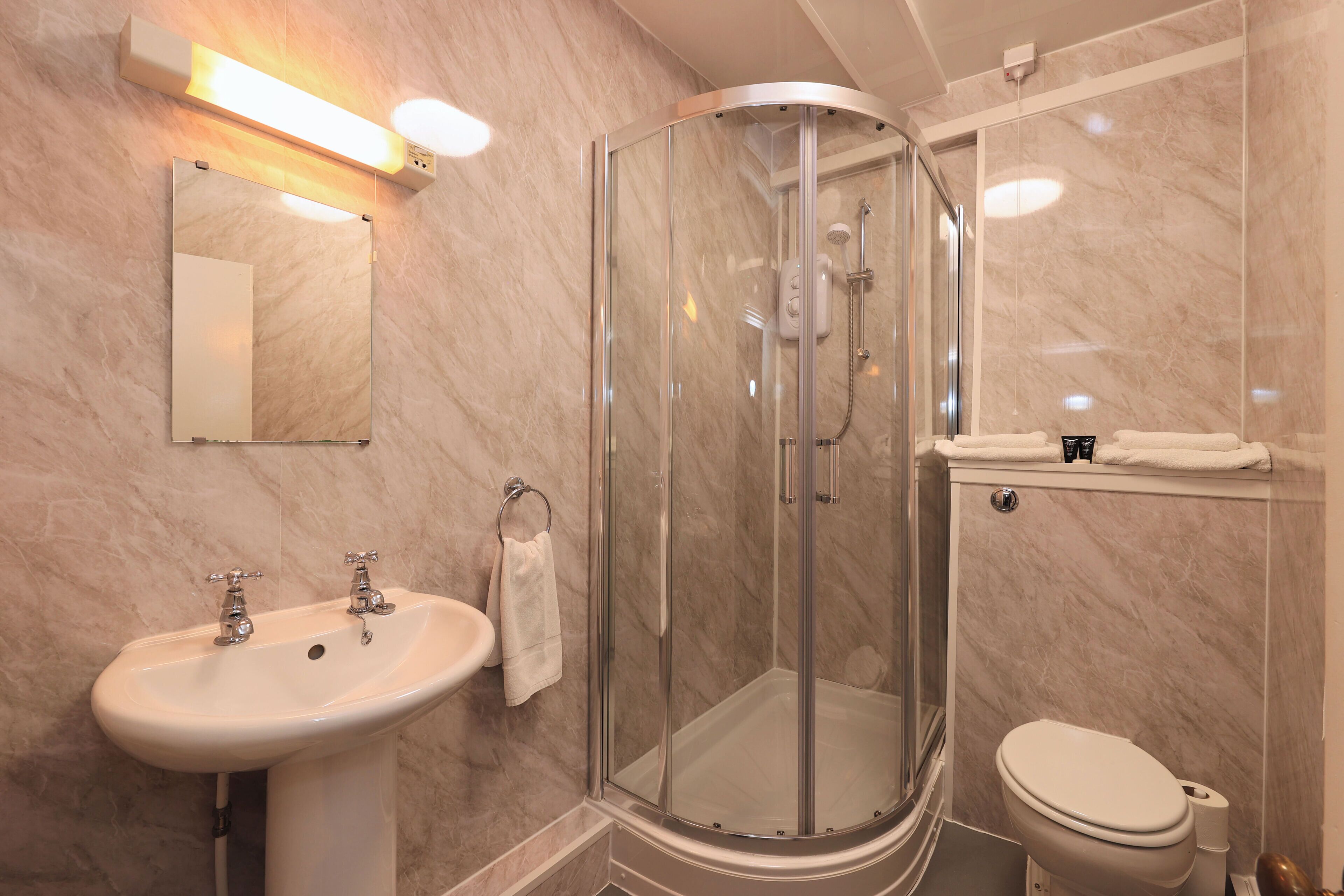 Een moderne badkamer met een glazen douchecabine, een wastafel en een toilet.