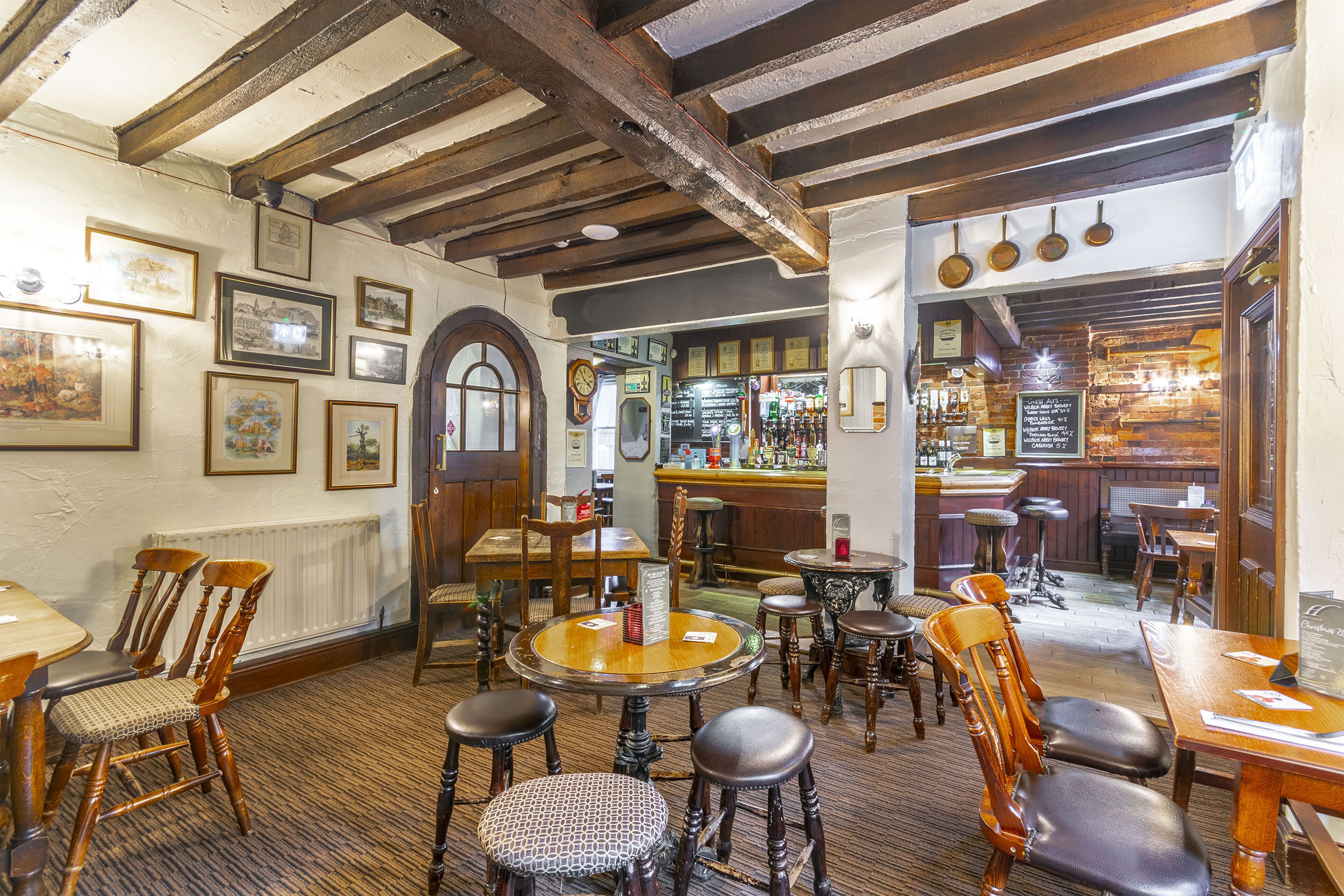 Una posada tradicional con muebles de madera, una zona de bar y varias fotografías enmarcadas en las paredes.