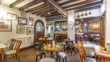 Una posada tradicional con muebles de madera, una zona de bar y varias fotografías enmarcadas en las paredes.