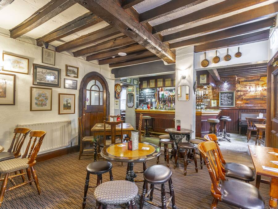Una posada tradicional con muebles de madera, una zona de bar y varias fotografías enmarcadas en las paredes.