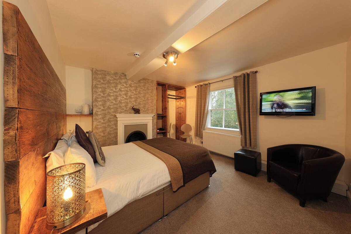 A bedroom with a bed, a TV, a chair, and a lamp.