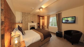 Un dormitorio con cama, televisor, sillón y lámpara.