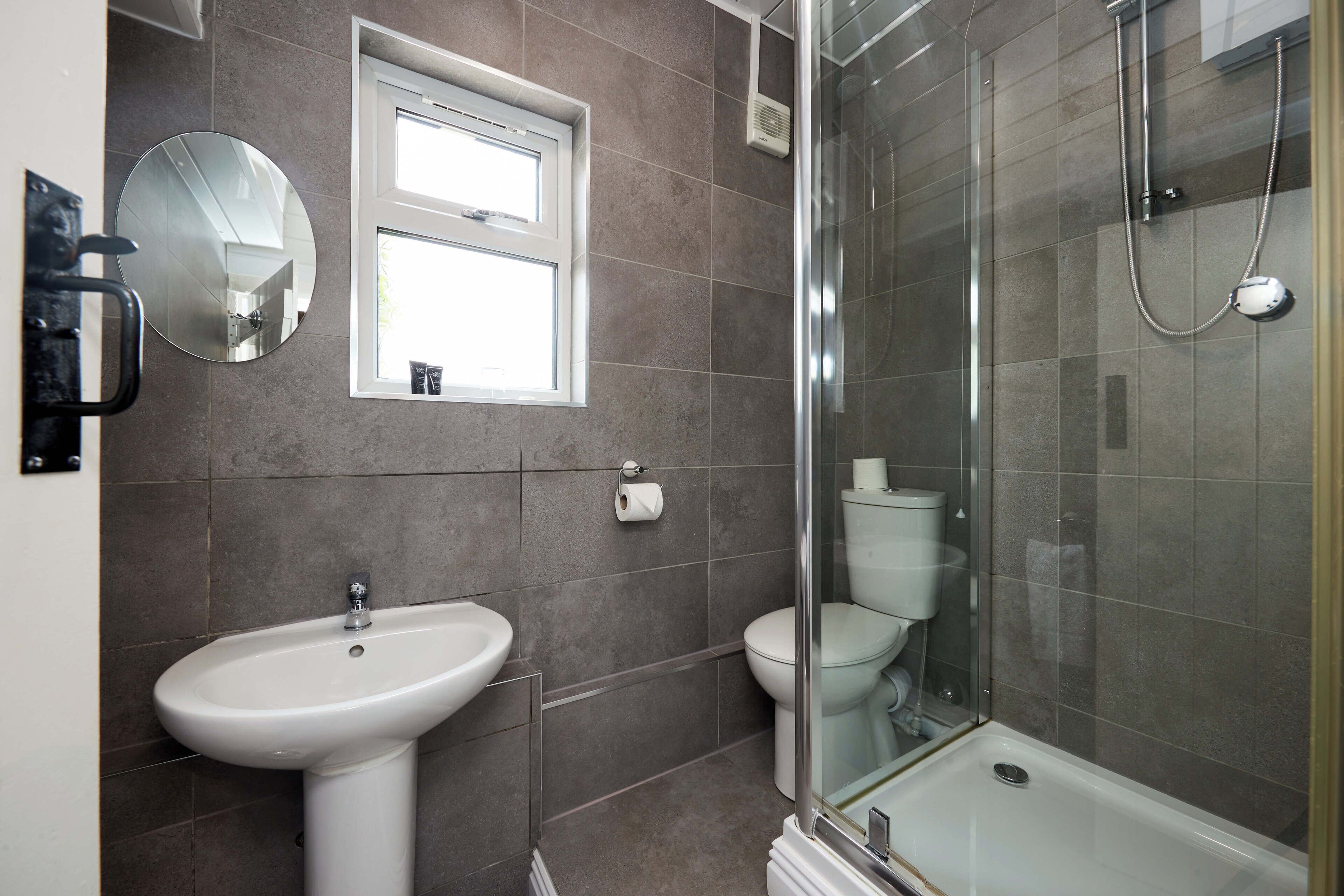 A bathroom with a sink, toilet, and glass-enclosed shower area.