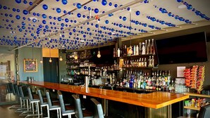 A bar with a long counter, multiple stools, and a ceiling adorned with blue spherical decorations. - Hotel Kilbourne Downtown Sandusky (Sandusky)