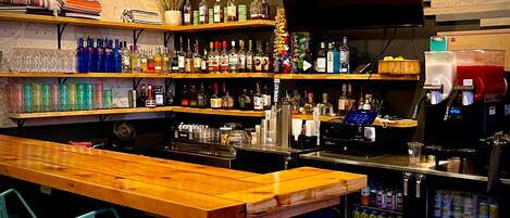 A bar area with shelves of liquor bottles, a TV, and a refrigerator stocked with beverages.