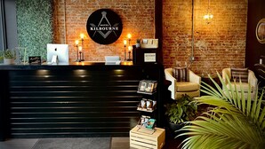 A reception desk with a black counter, a sign reading "Hotel Kilbourne," and a brick wall. - Hotel Kilbourne Downtown Sandusky (Sandusky)
