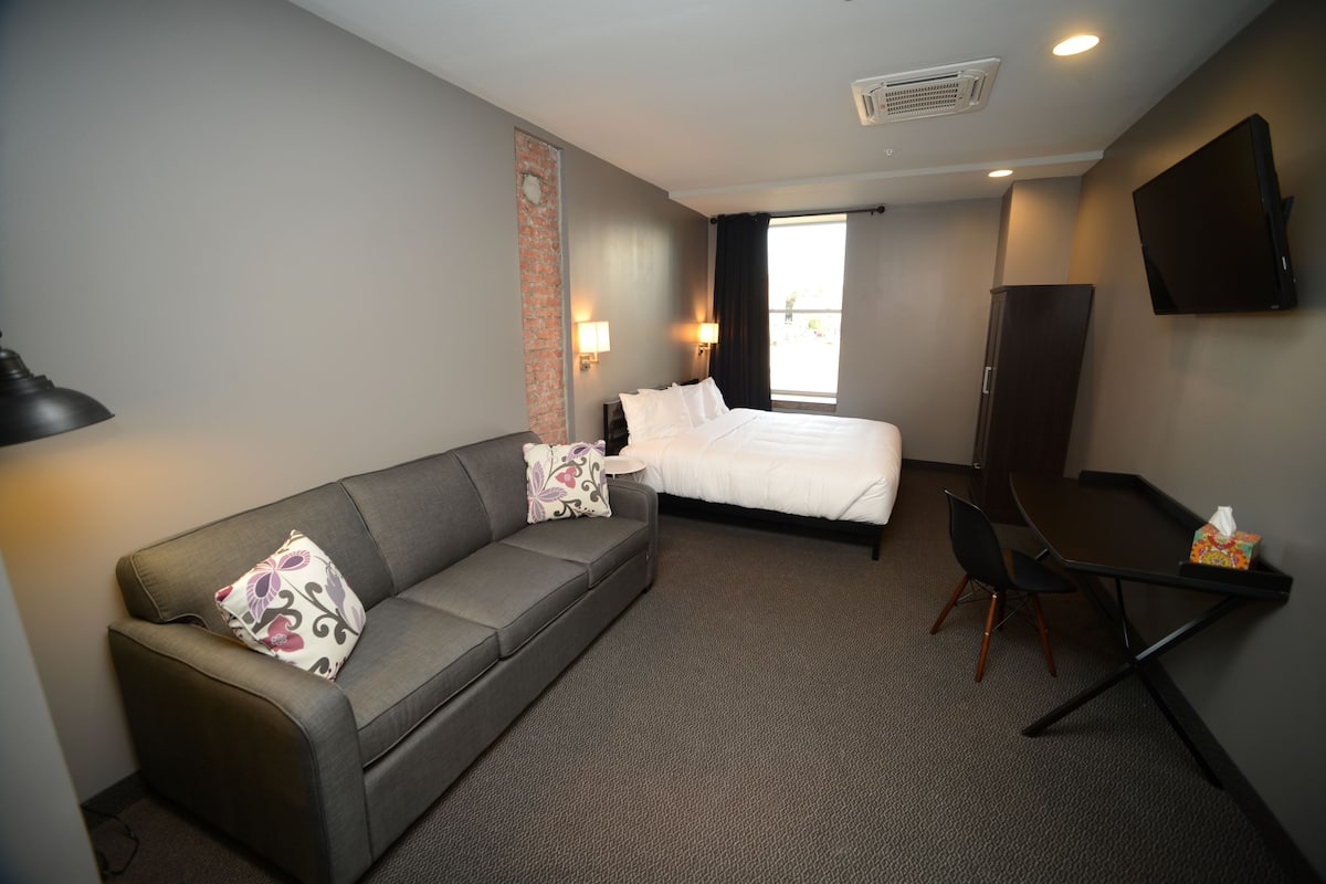 Une chambre d’hôtel avec un lit, un canapé, un bureau et une télévision.