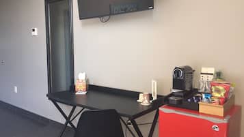 Une pièce de taille modeste comprenant un bureau, une chaise et un petit coin cuisine.
