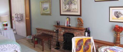A room with a fireplace, a bed, a dining table, and various framed pictures on the wall.