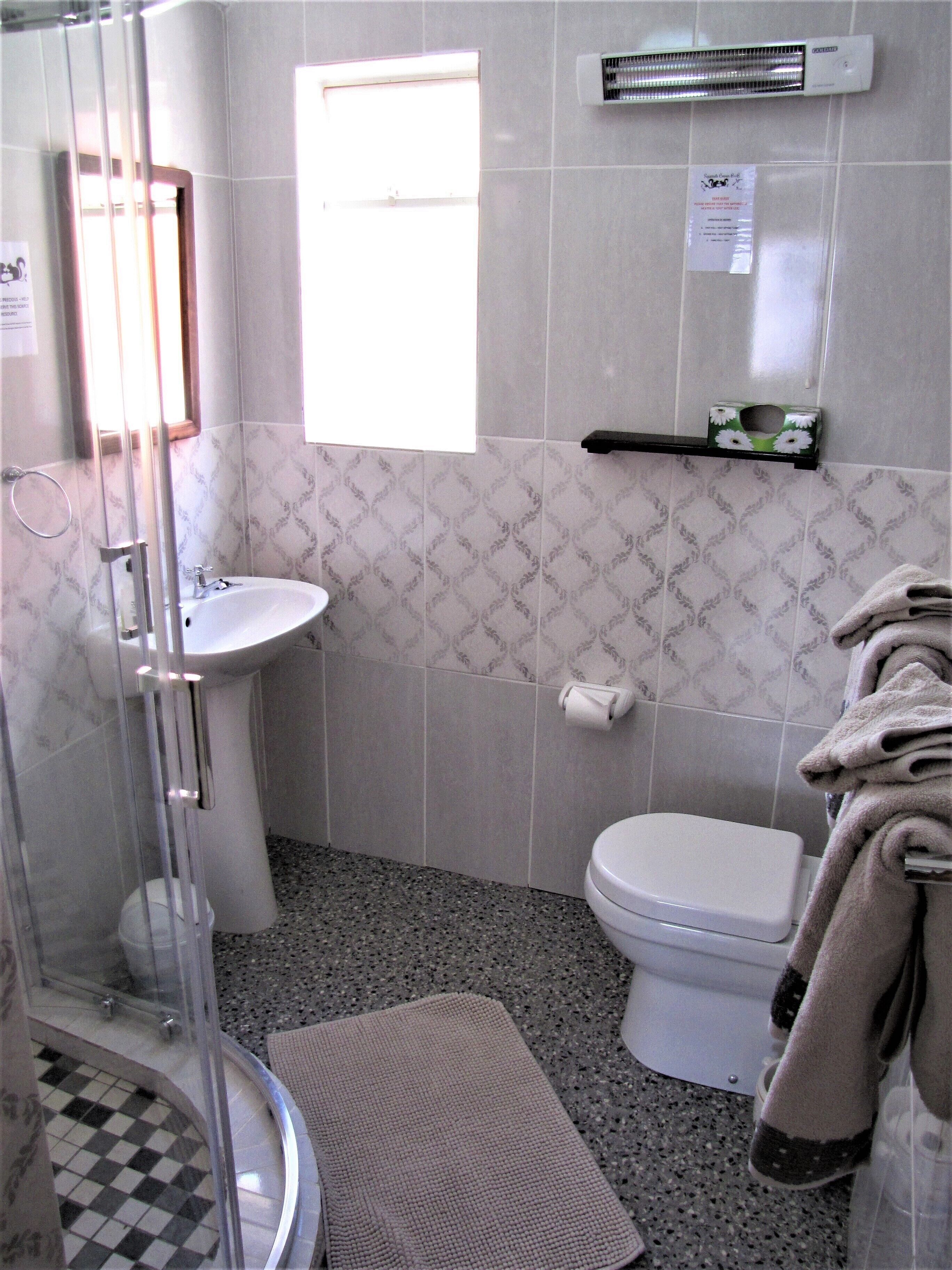 A bathroom with a shower, sink, toilet, and a towel rack.
