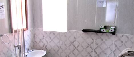 A bathroom with a shower, sink, toilet, and a towel rack.