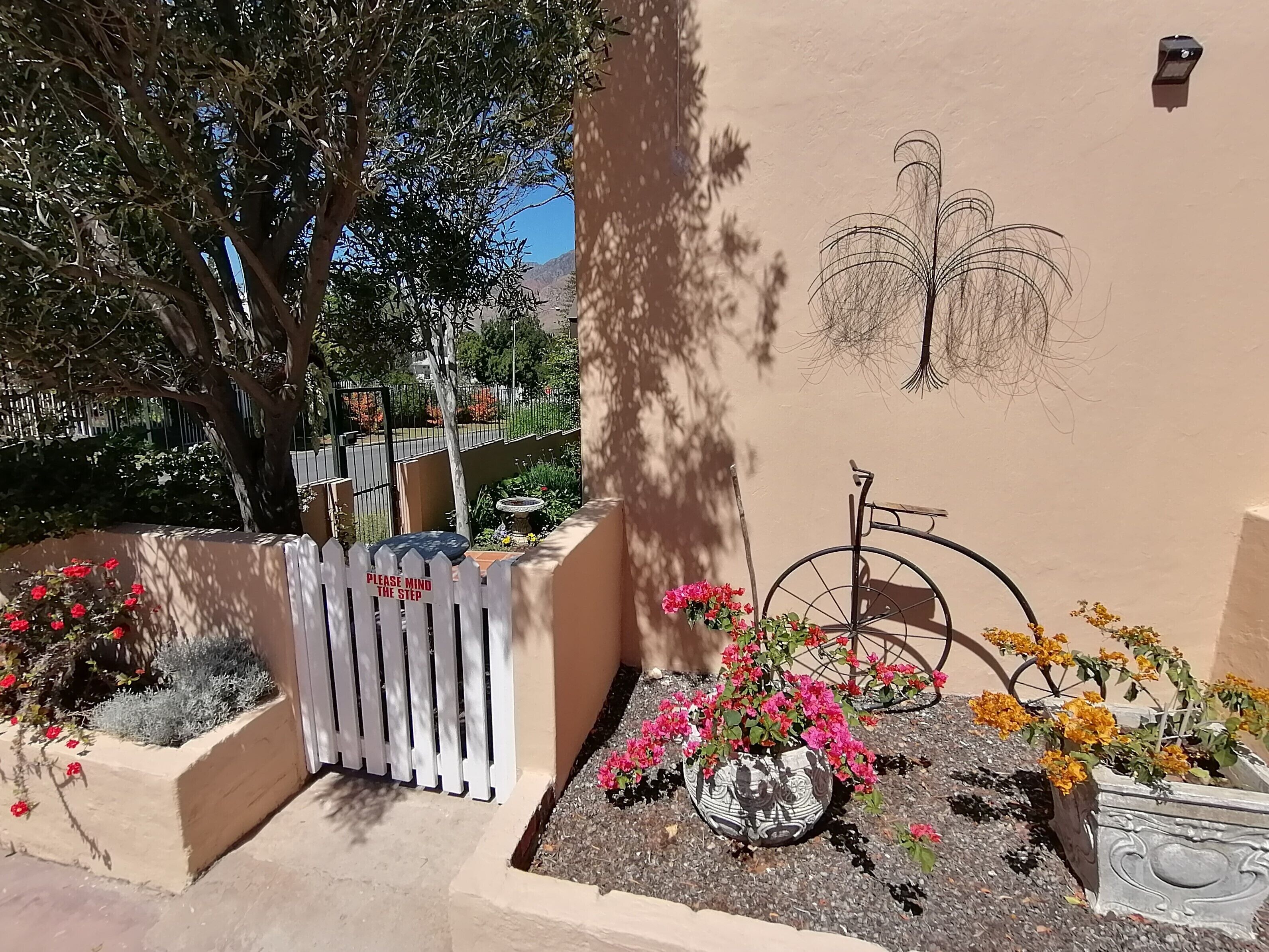 Un jardín con cerca blanca de piquetes, una bicicleta y macetas con flores.