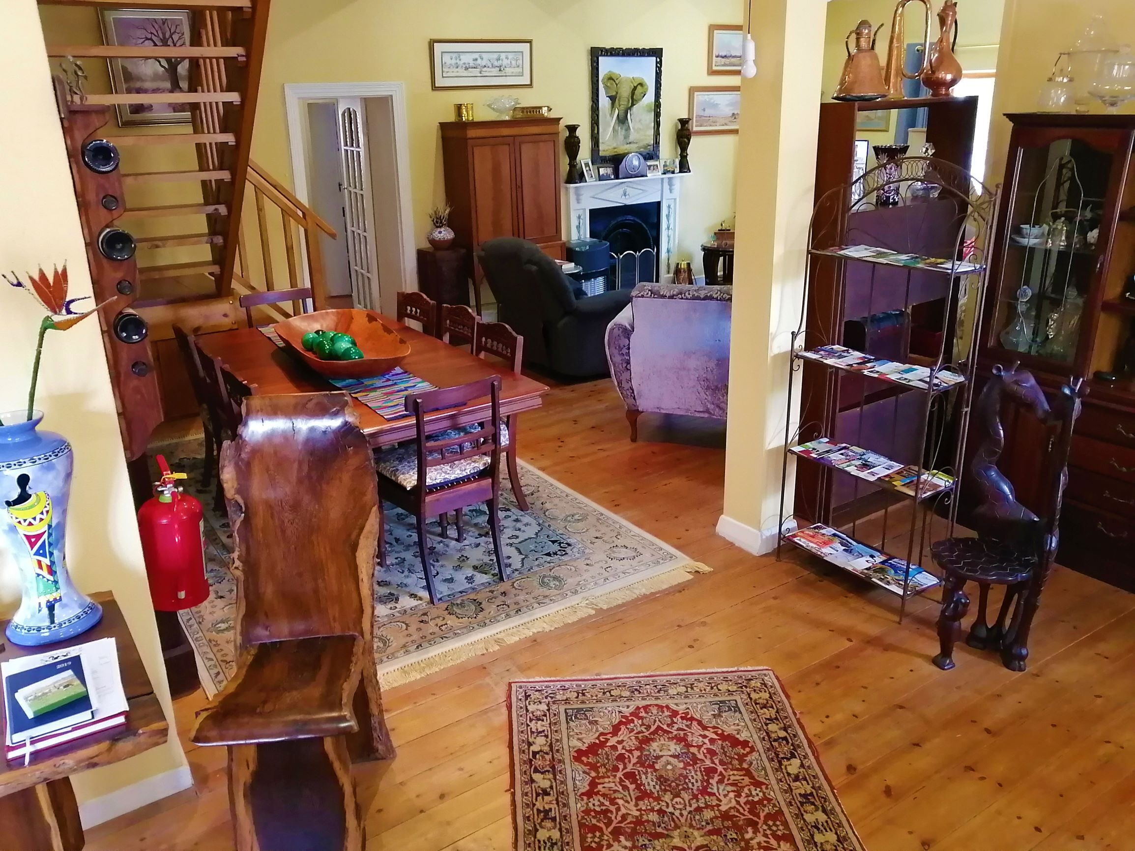 Una sala de estar acogedora con una mesa de comedor de madera, sillas, chimenea y una estantería.