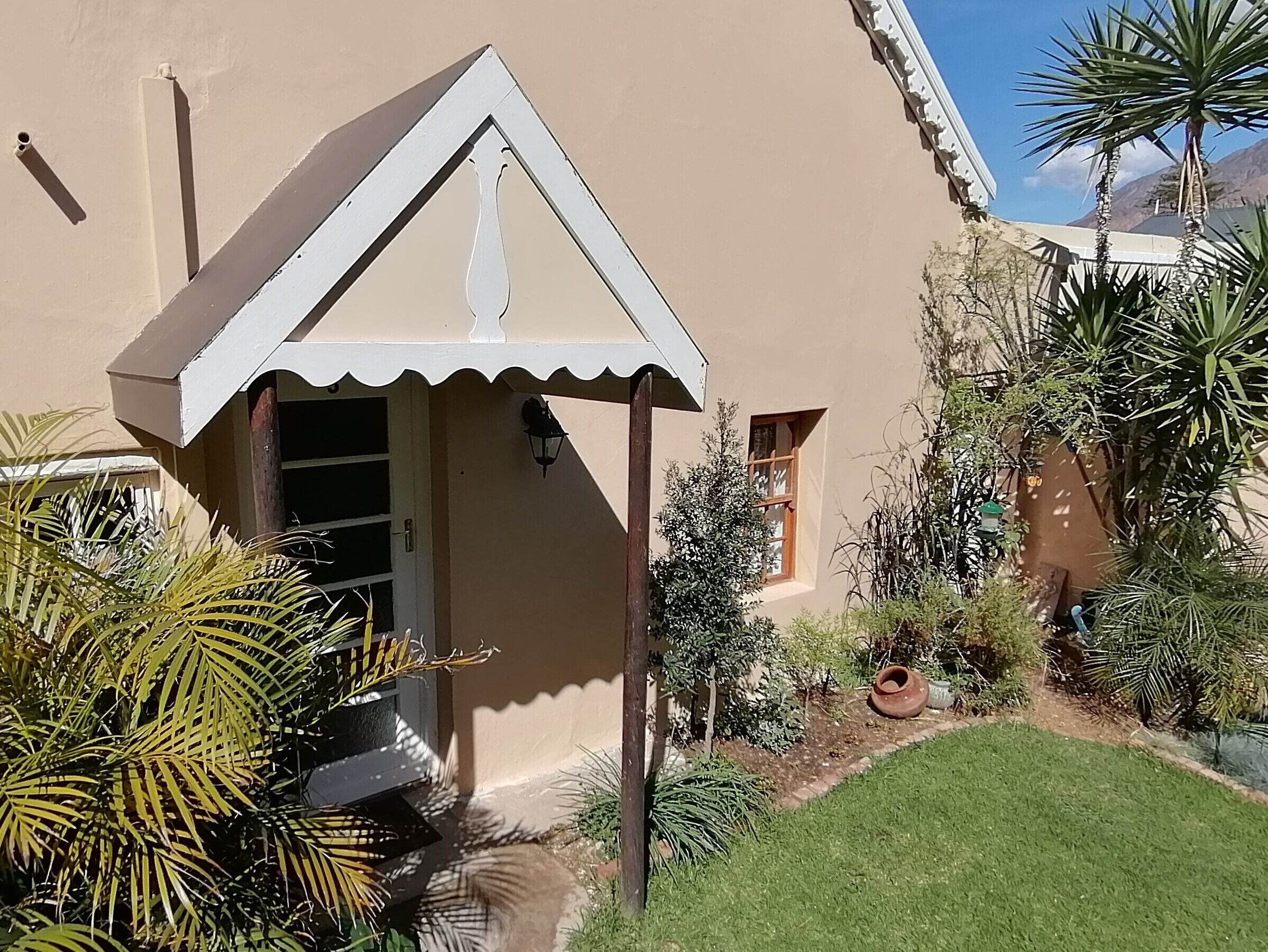 A small house with a white roof and a garden with various plants.