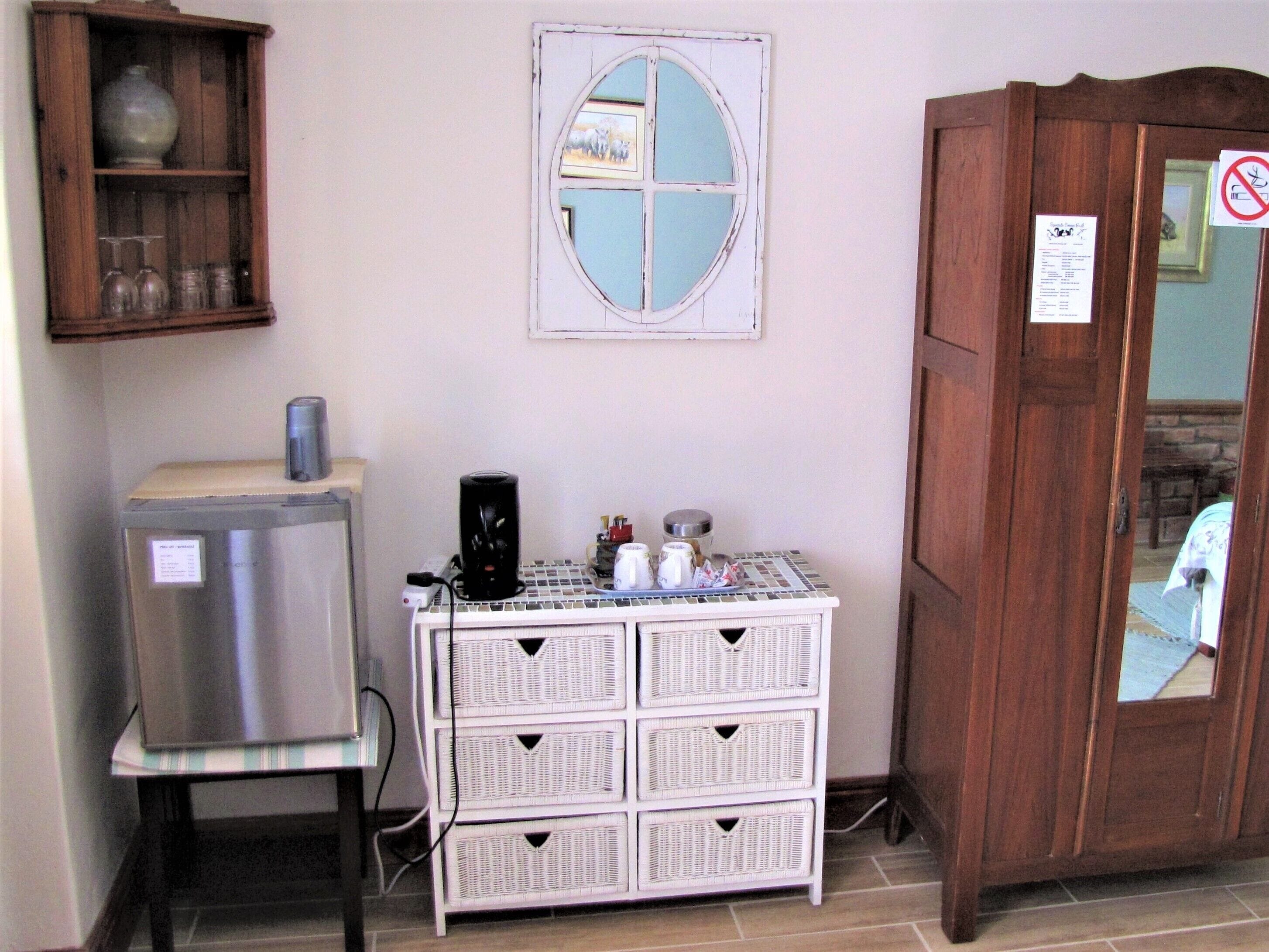 A kitchen with a refrigerator, a coffee maker, a white wicker storage unit, and a wooden cabinet with a window.
