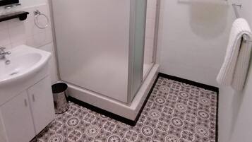 Une salle de bain avec une douche, un lavabo et des carreaux de sol à motifs.