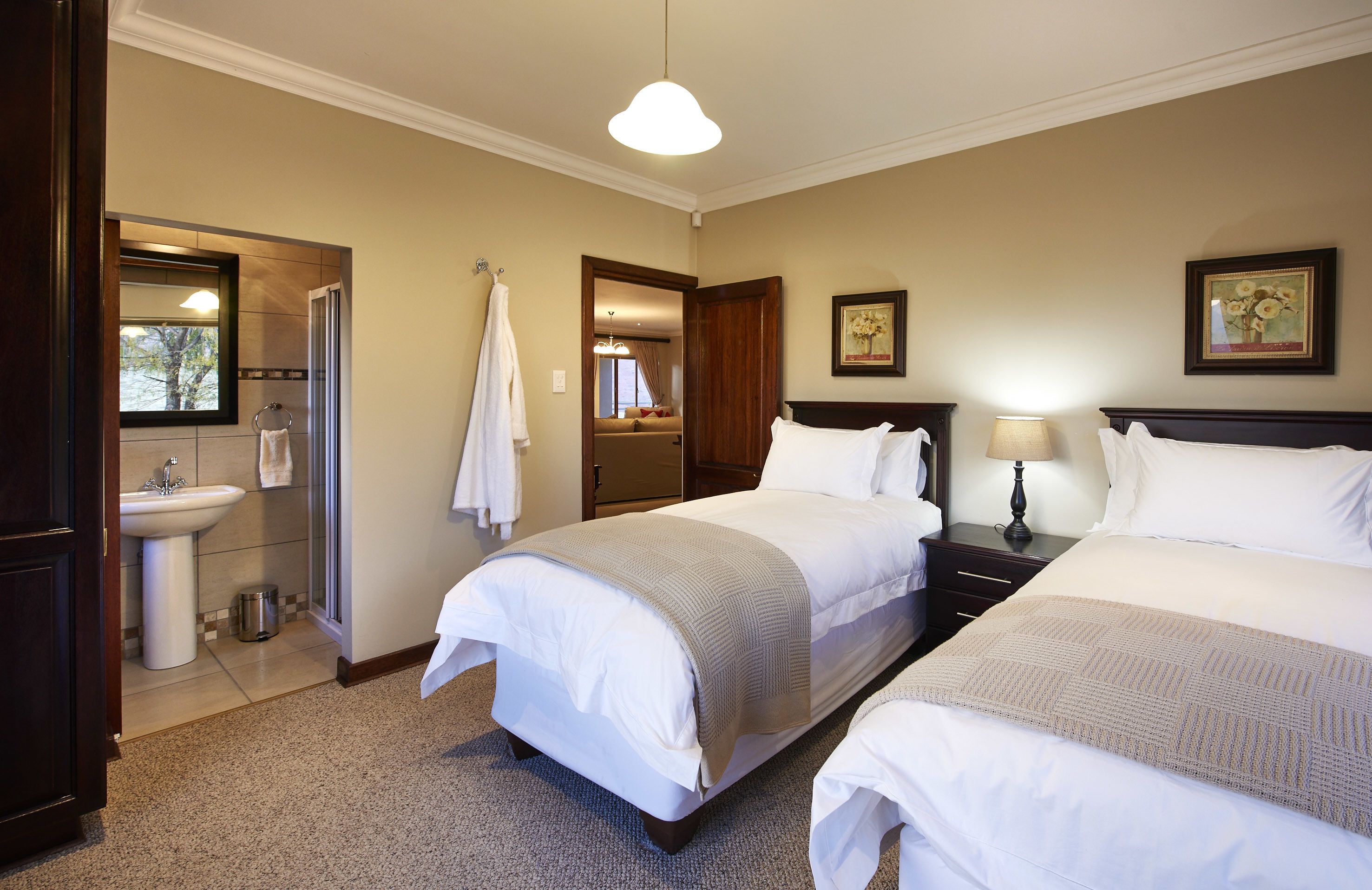A hotel room with two beds, a sink, a mirror, and a framed picture on the wall.