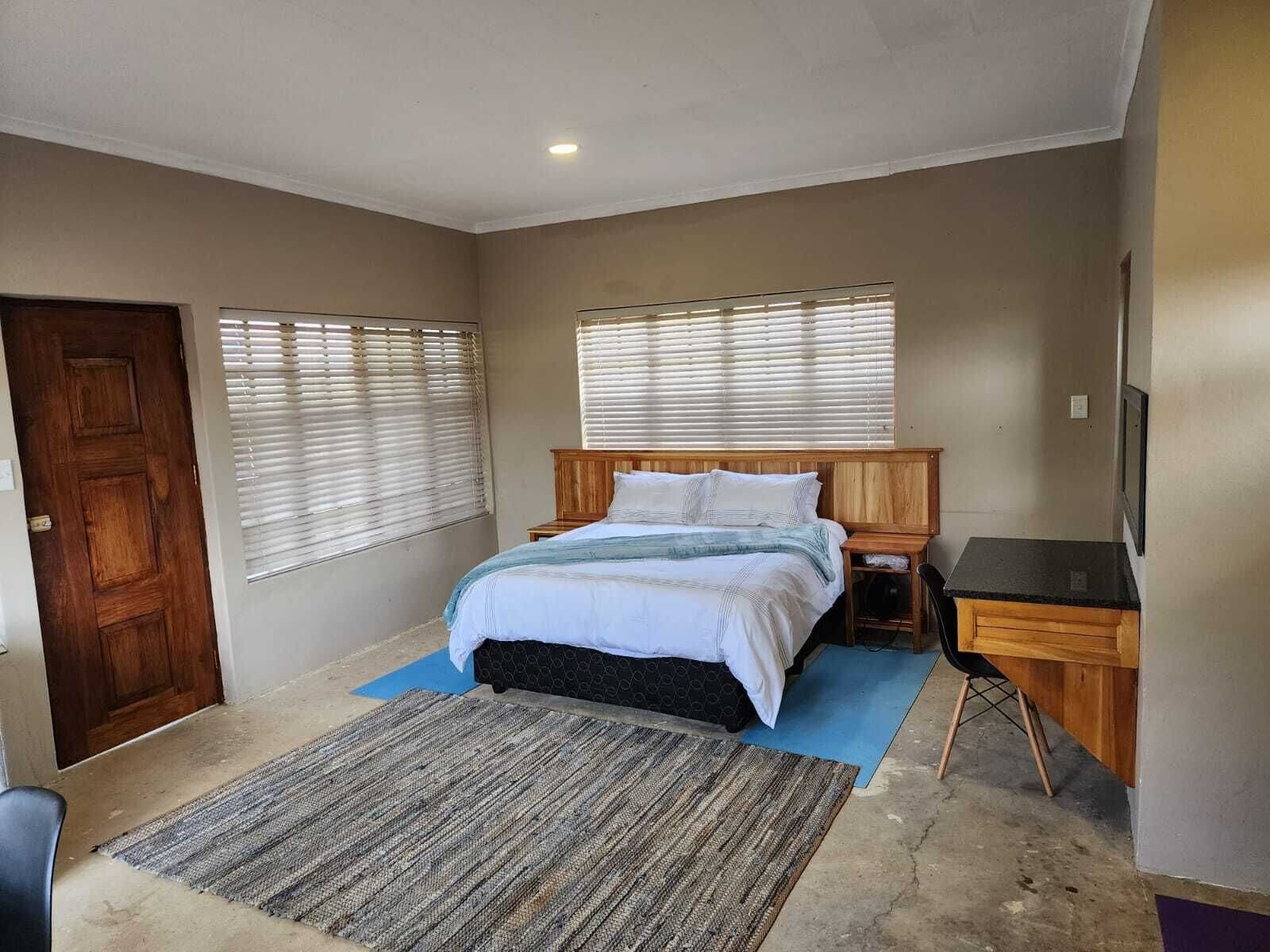Een slaapkamer met een houten bed, een bureau en een stoel.