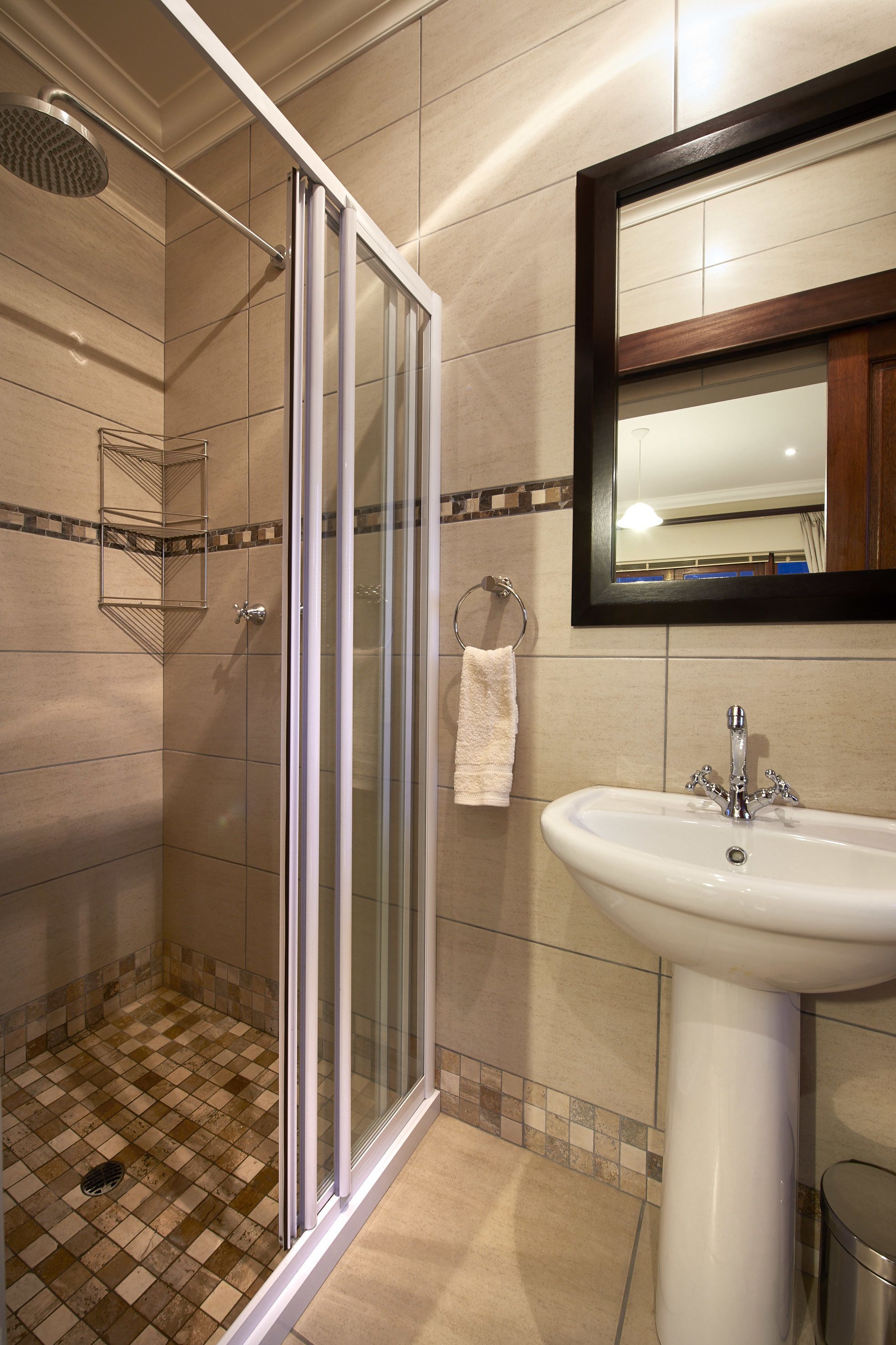 A bathroom with a glass-enclosed shower, a sink, and a mirror.