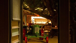 An open doorway leading to a dimly lit interior space with a vintage tractor and rustic decor. - Casa Forno Country Hotel (Otjiwarongo)