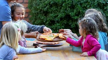 Children enjoy a family pizza night in a casual outdoor setting.