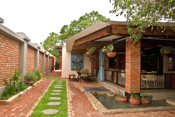 A courtyard with a brick wall, a small pool, potted plants, and outdoor seating.