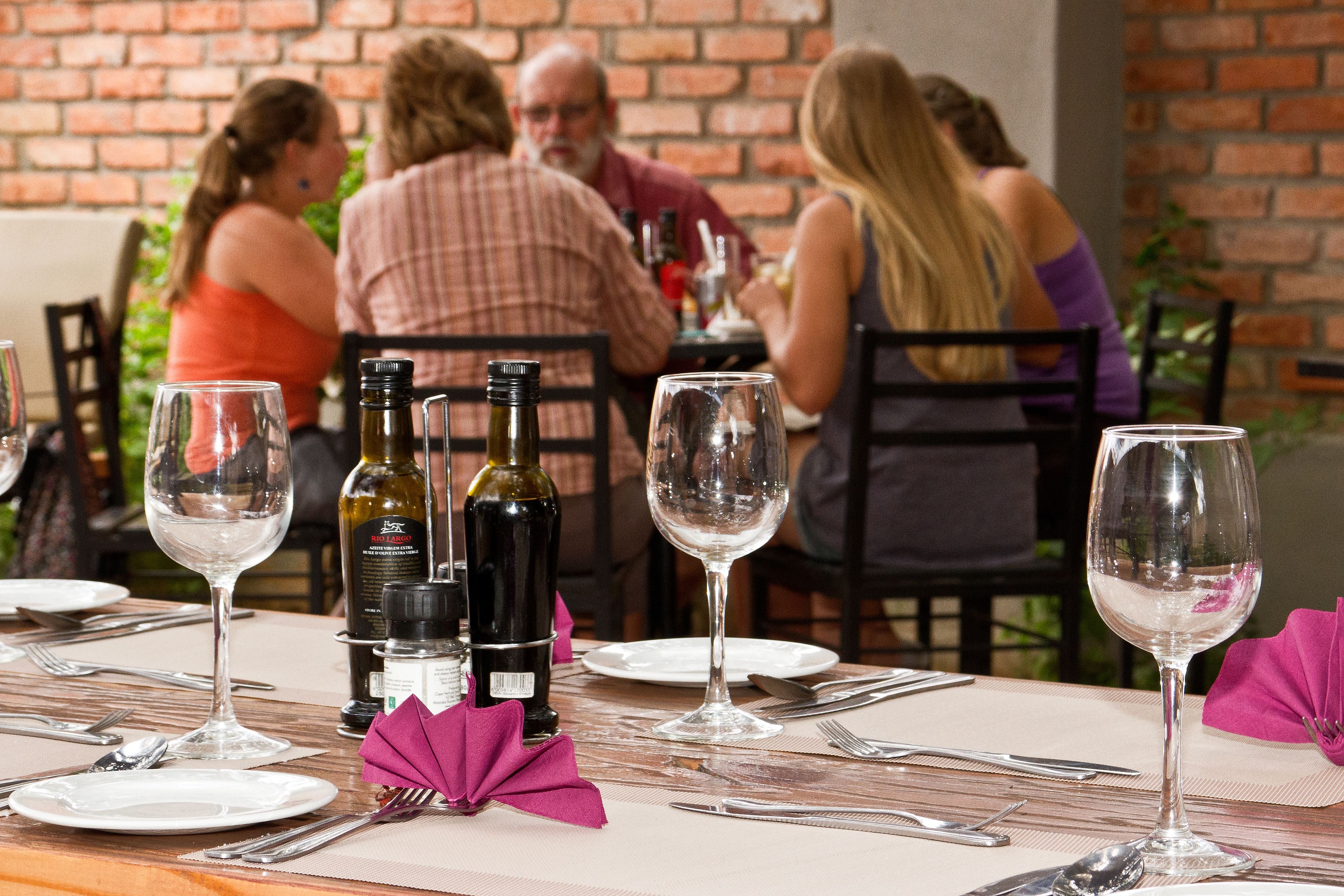 A dining table set for a meal with wine bottles and glasses.