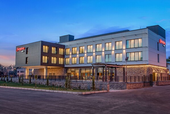 A modern hotel with a flat roof, multiple windows, and a visible entrance.