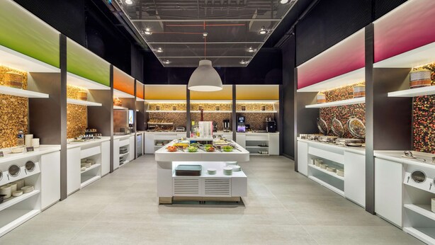 Ein modernes Buffet mit mehreren Servierstationen, an denen verschiedene Speisen und Besteck bereitstehen.