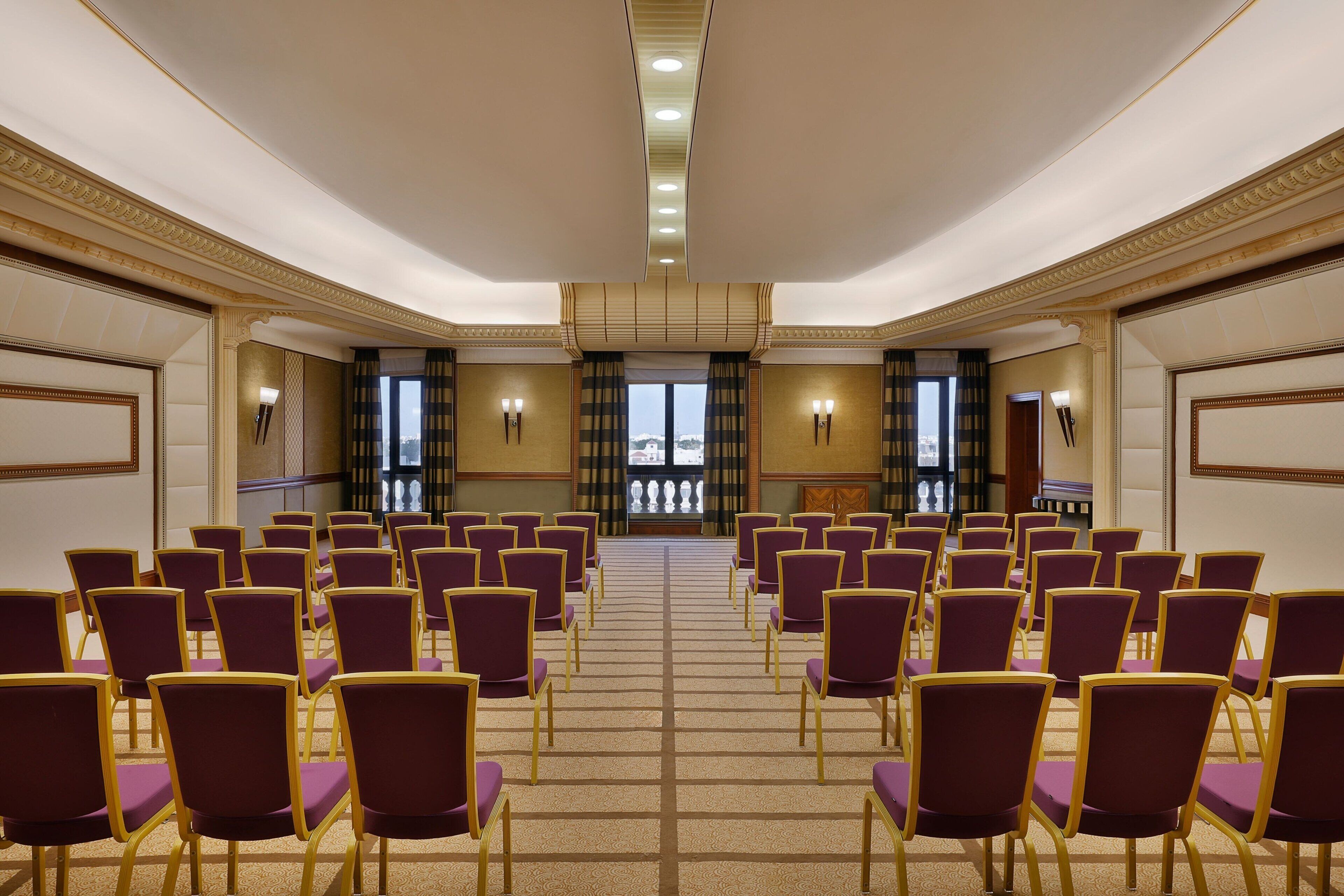 Un salón de conferencias con hileras de sillas moradas y un atril al frente.