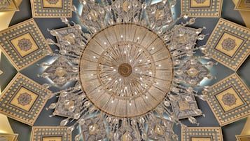 Un techo con un diseño circular central rodeado de patrones geométricos y adornos de cristal.
