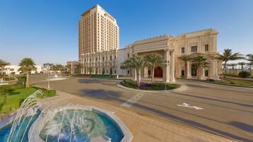 A large hotel with a prominent fountain, a grand entrance, and a tall building in the background.