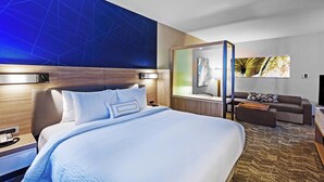 Une chambre d’hôtel moderne avec un grand lit, un canapé, un bureau et un miroir.