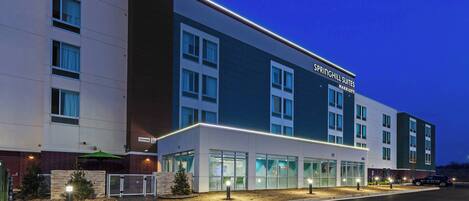 Ett modernt hotell med ett platt tak, stora fönster och en skylt med texten ”Springhill Suites Marriott”.
