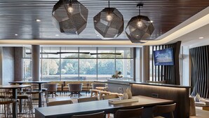 Un espace de salle à manger moderne, doté d’une longue table, de nombreuses chaises et de luminaires suspendus.
