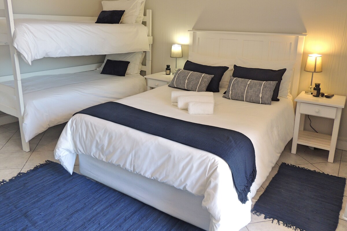 Une chambre d’hôtel avec deux lits, une table de chevet avec une lampe et une petite table.