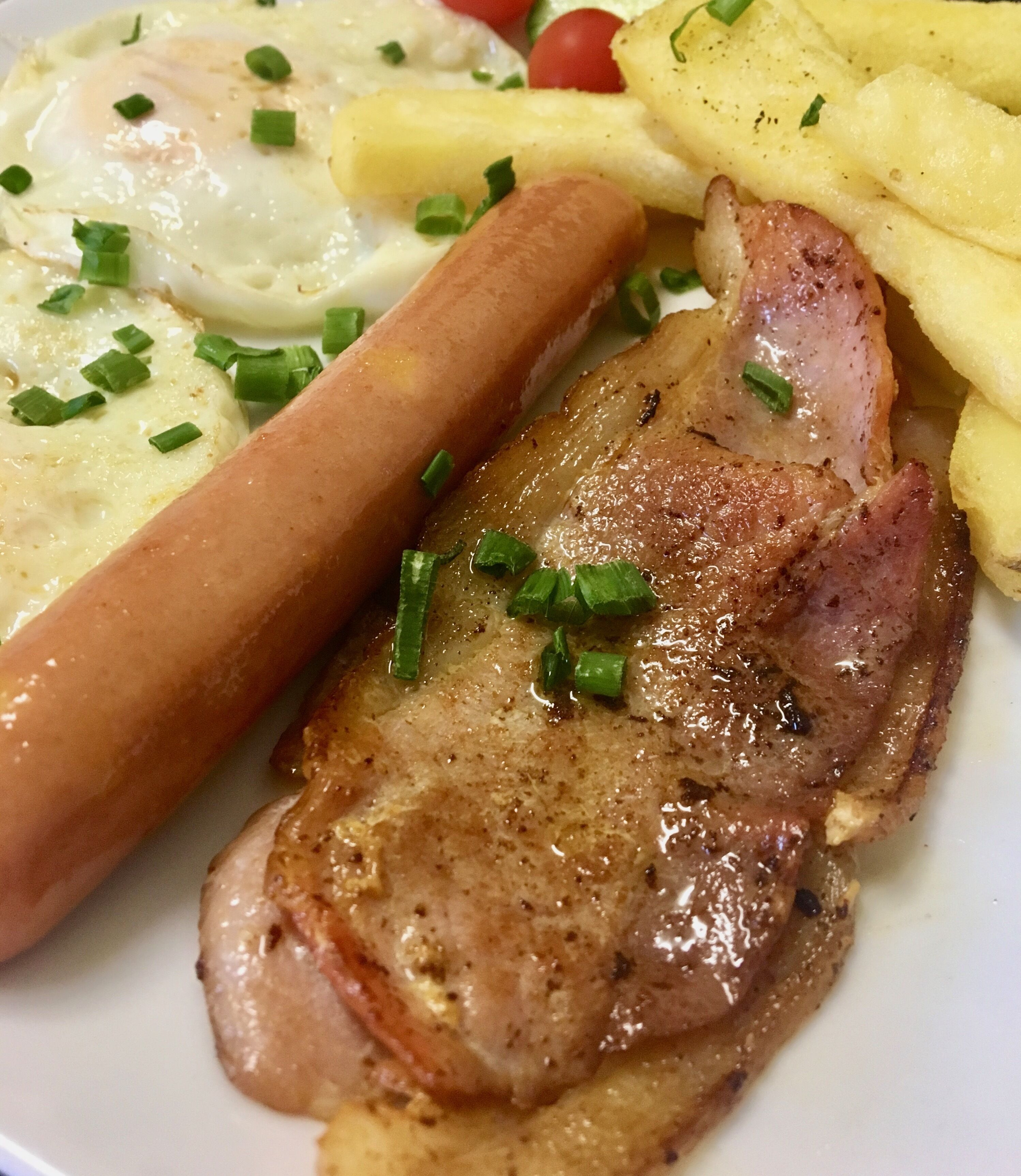 A plate with a grilled ham, a sausage, and a fried egg.