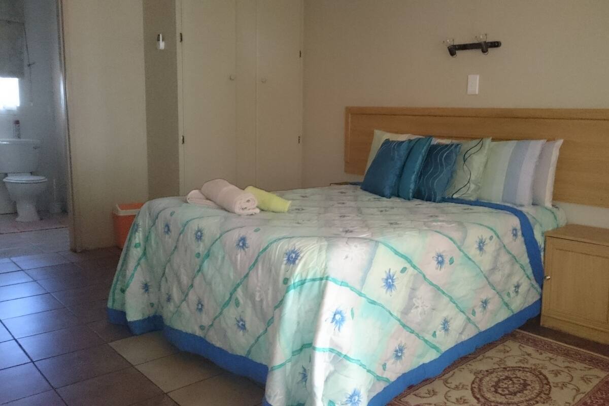 A bedroom with a bed, a wooden headboard, a bedside table, and a small cabinet.